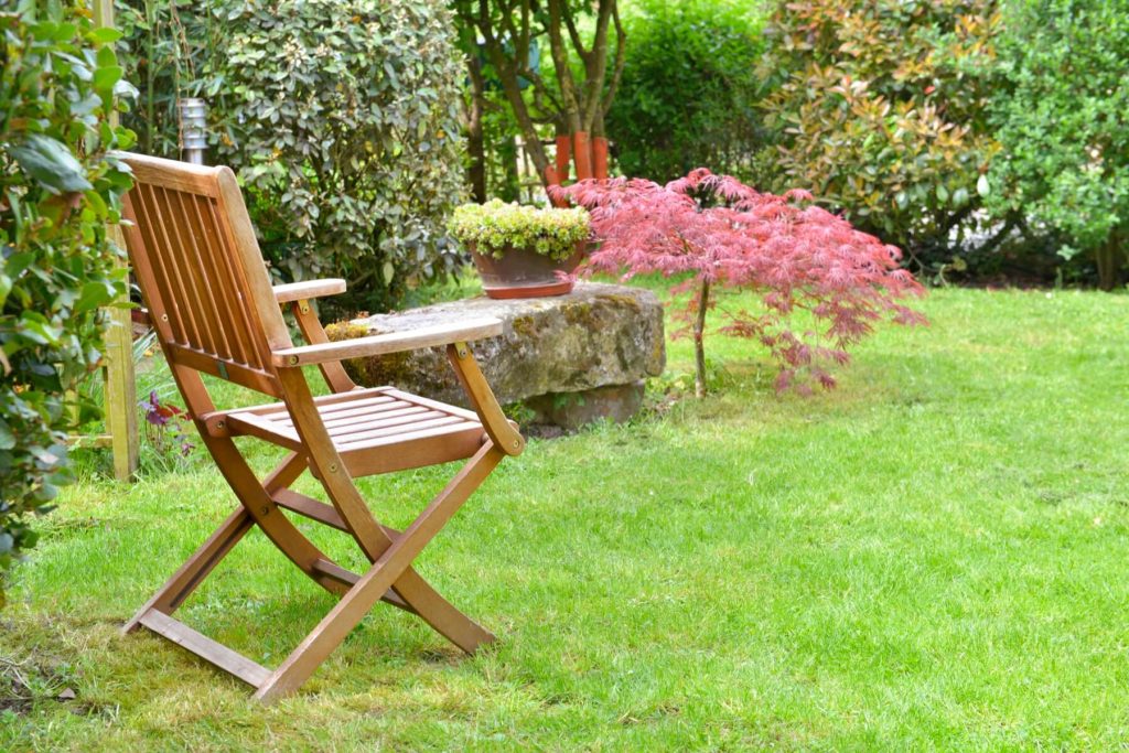 ristrutturazione giardino con sedia in legno e pietra